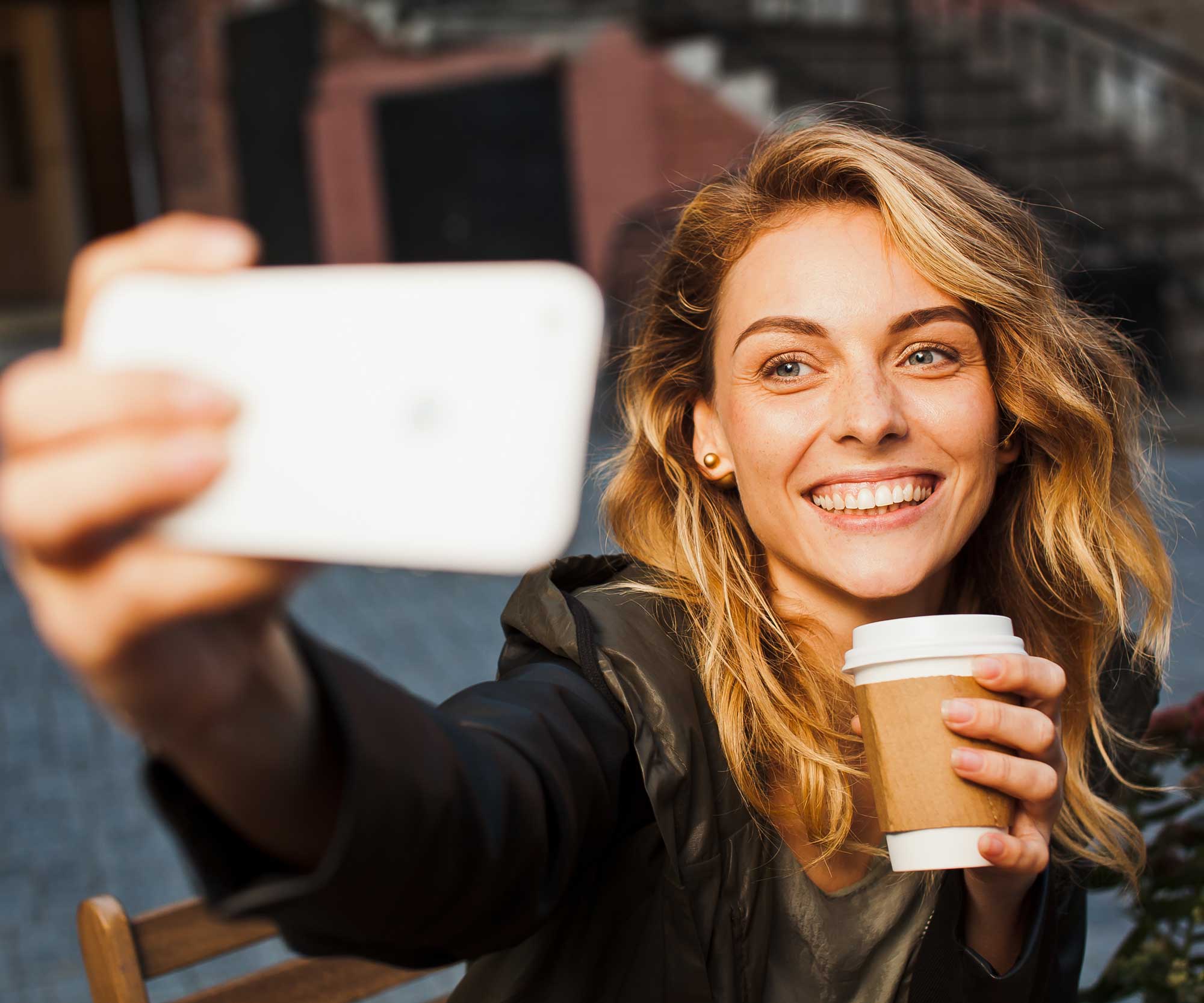 woman with coffee taking selfie